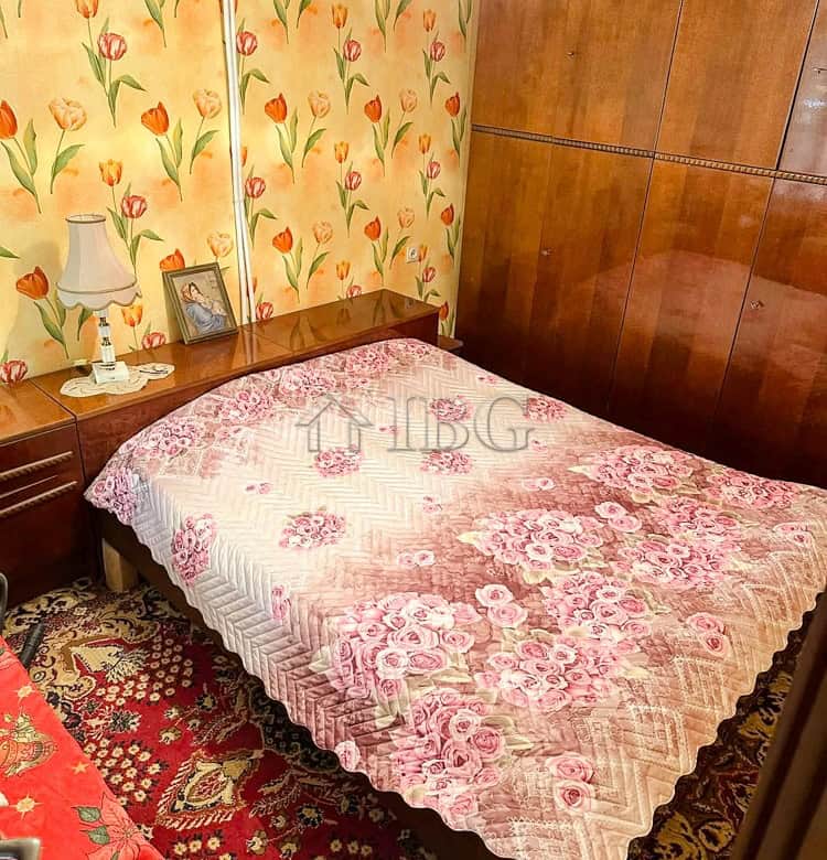 Comfortable bedroom featuring floral wallpaper, a wooden wardrobe, and vintage-style furnishings.