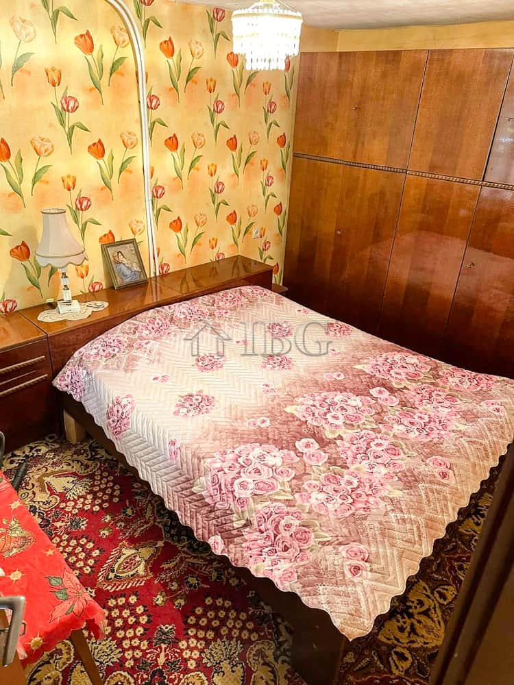 Comfortable bedroom featuring floral wallpaper, a wooden wardrobe, and vintage-style furnishings.