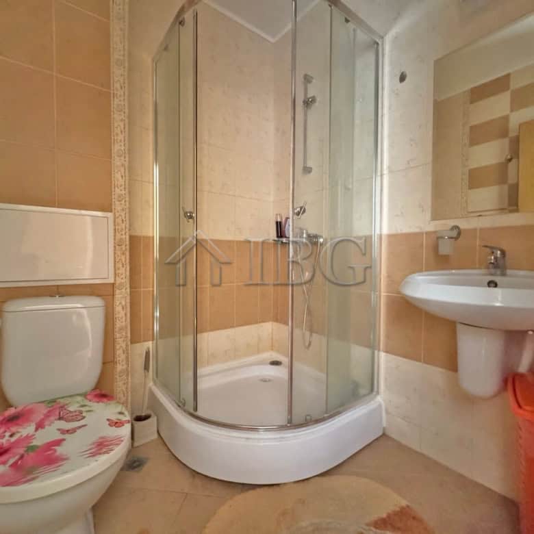 Bathroom with shower enclosure, toilet, and sink in Sunny Beach apartment.