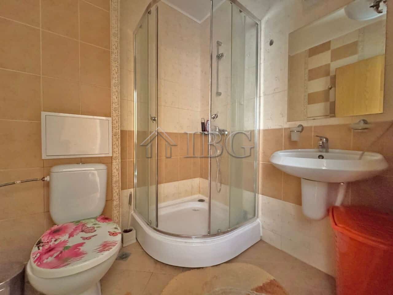 Bathroom with shower enclosure, toilet, and sink in Sunny Beach apartment.
