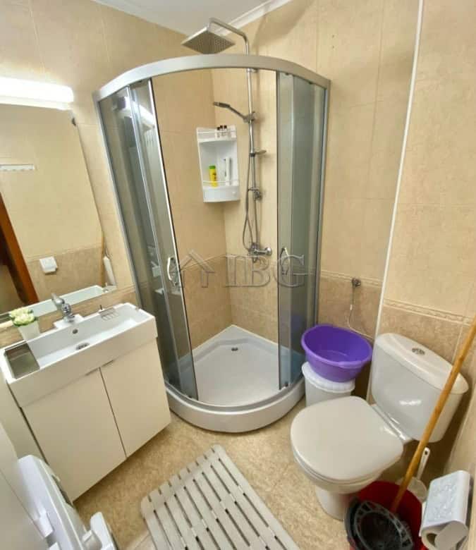 Bright bathroom with shower enclosure, toilet, and sink in a compact apartment.