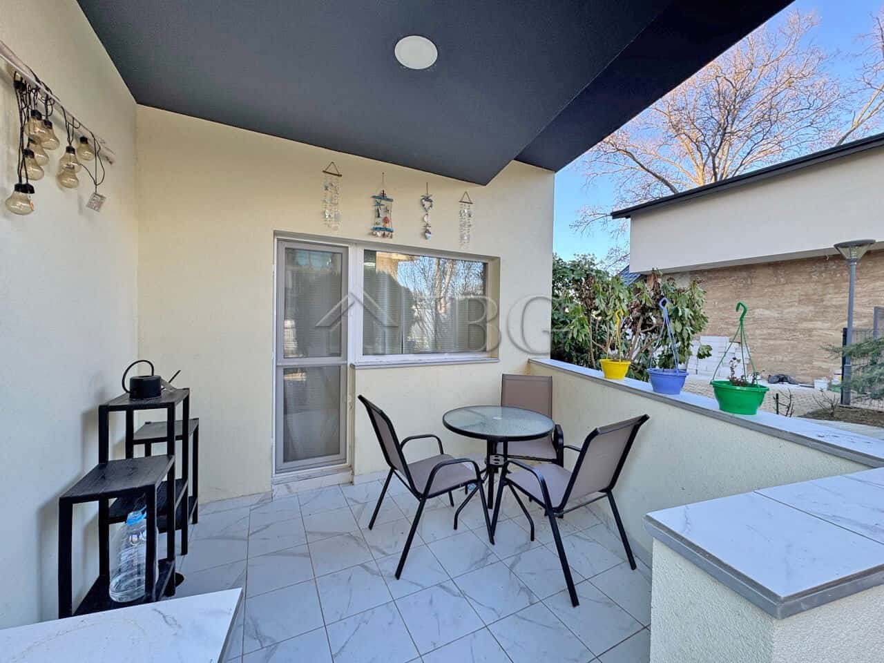 Bright outdoor terrace with seating area and potted plants, perfect for relaxing in the sunny beach.