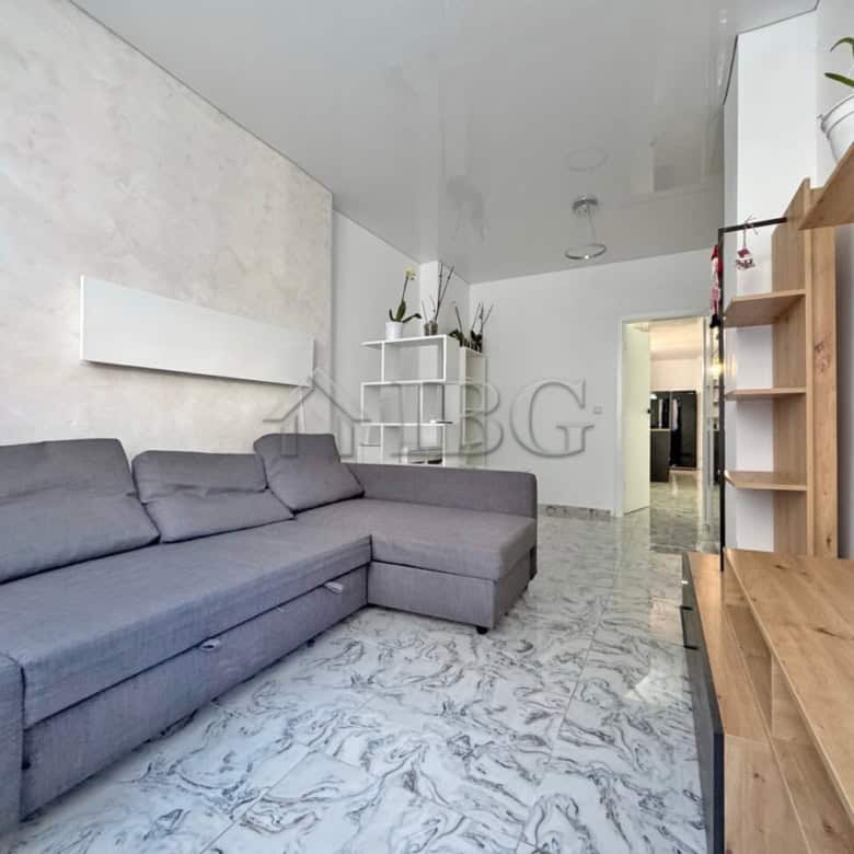 Bright living space featuring a large gray sofa and access to a spacious terrace.