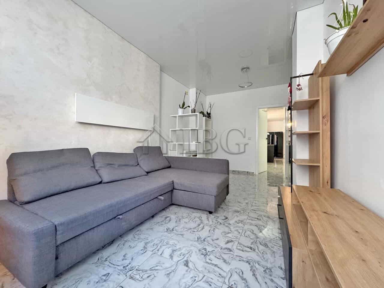 Bright living space featuring a large gray sofa and access to a spacious terrace.