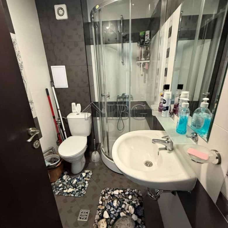 Bright bathroom featuring a shower enclosure, toilet, and sink with toiletries in Sveti Vlas.