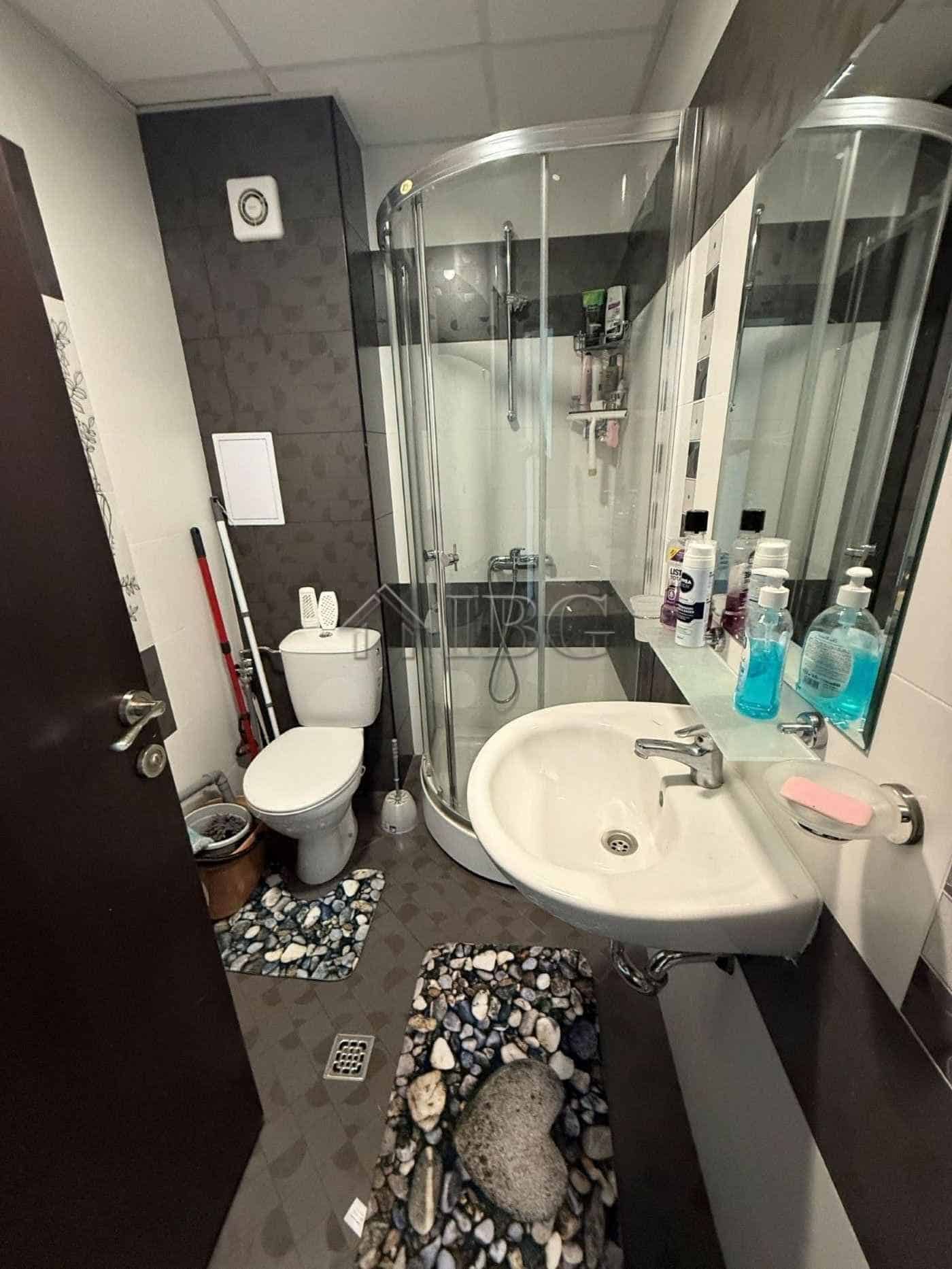Bright bathroom featuring a shower enclosure, toilet, and sink with toiletries in Sveti Vlas.