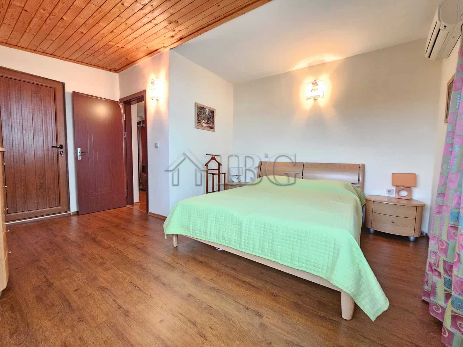 Bright bedroom in Sozopol apartment with sea view, wooden floors, and modern furnishings.