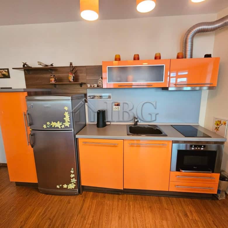 Bright, compact kitchen with refrigerator, oven, and stovetop.