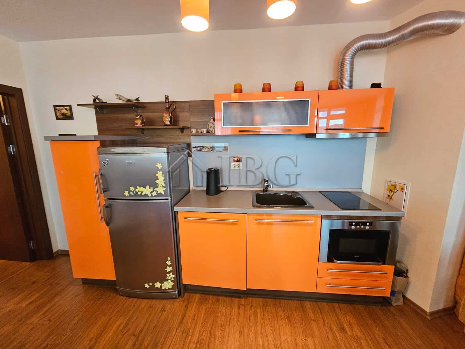 Bright, compact kitchen with refrigerator, oven, and stovetop.