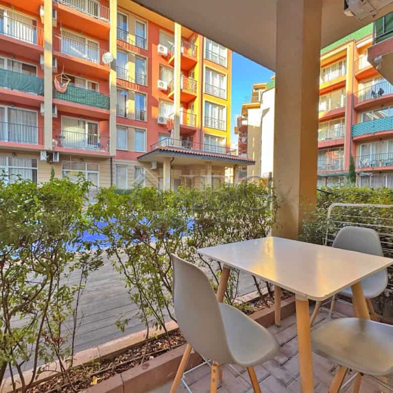 Balcony with seating overlooking pool and colorful apartment buildings in Sunny Beach.