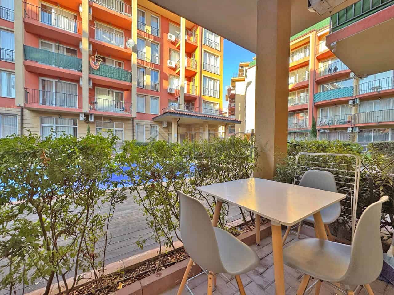 Balcony with seating overlooking pool and colorful apartment buildings in Sunny Beach.