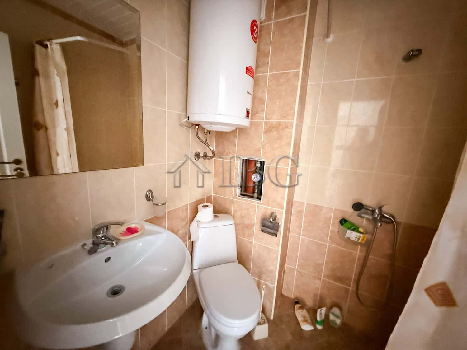 Compact studio bathroom with modern fixtures and water heater.