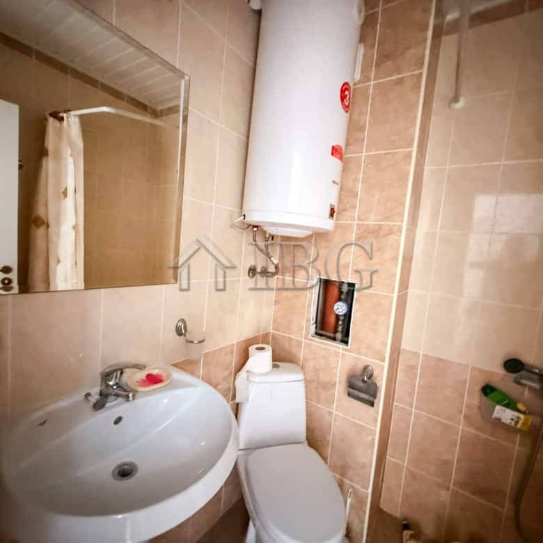 Small studio apartment bathroom with sink, toilet, and water heater in Sunny Beach.