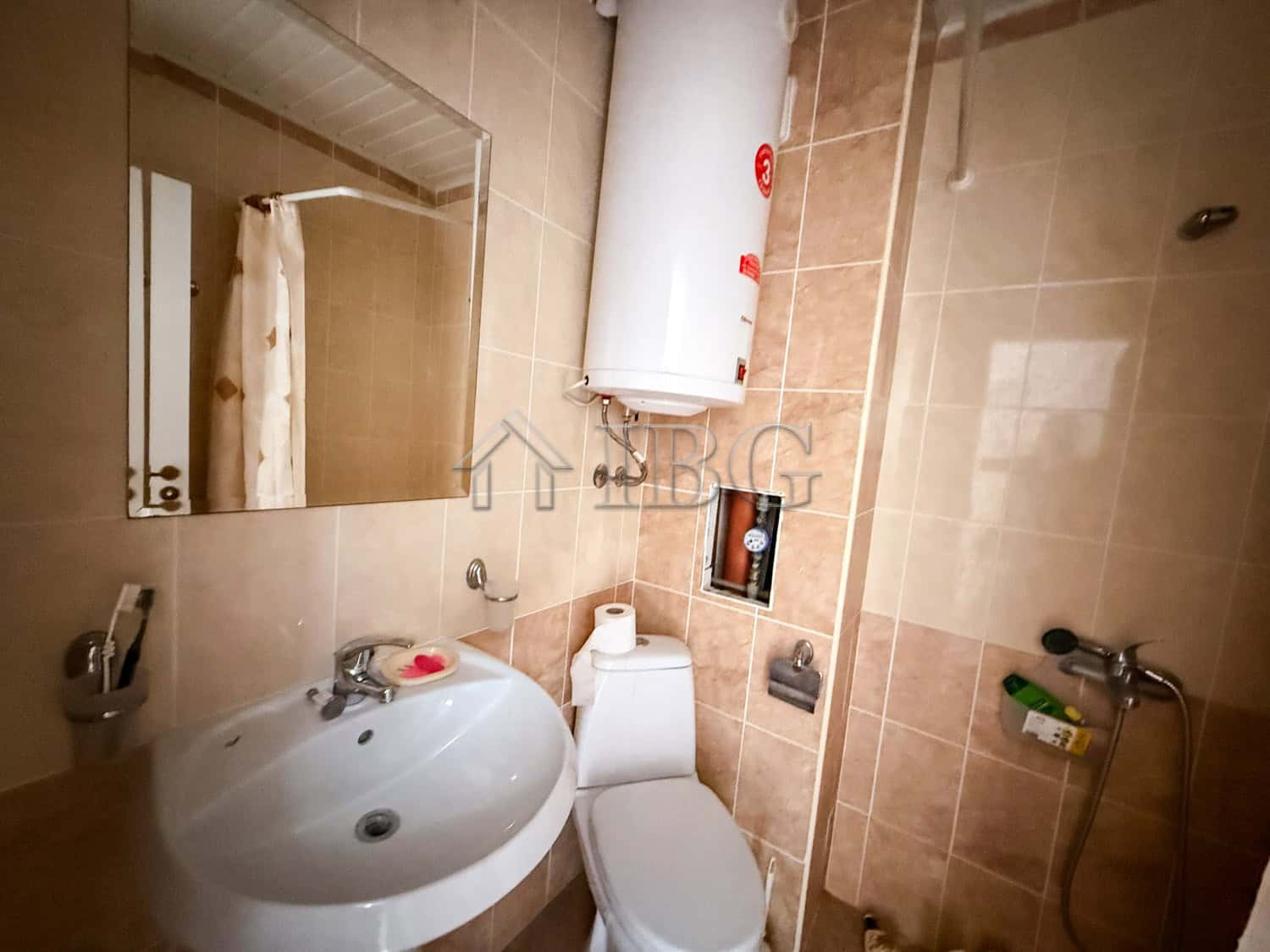 Small studio apartment bathroom with sink, toilet, and water heater in Sunny Beach.