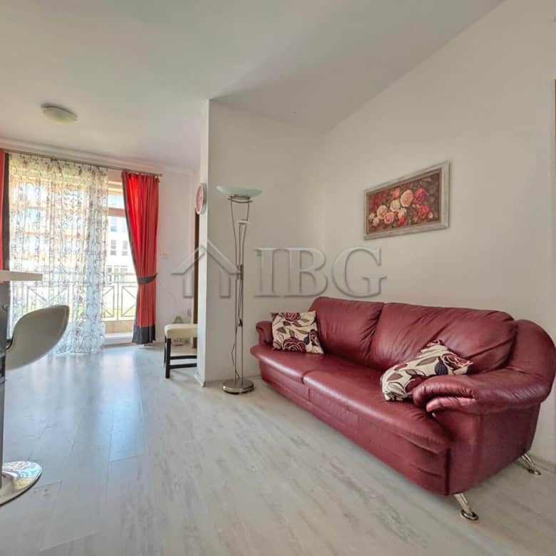 Bright living room with red sofa and large windows with red curtains.