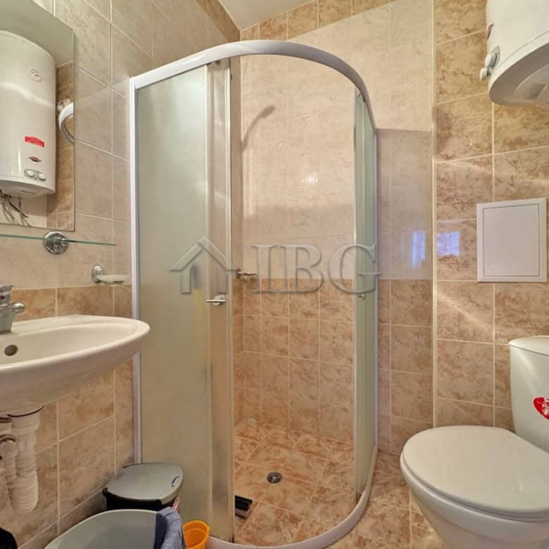 Bright bathroom with shower, toilet, and sink in a ground-floor apartment. Compact and functional de.
