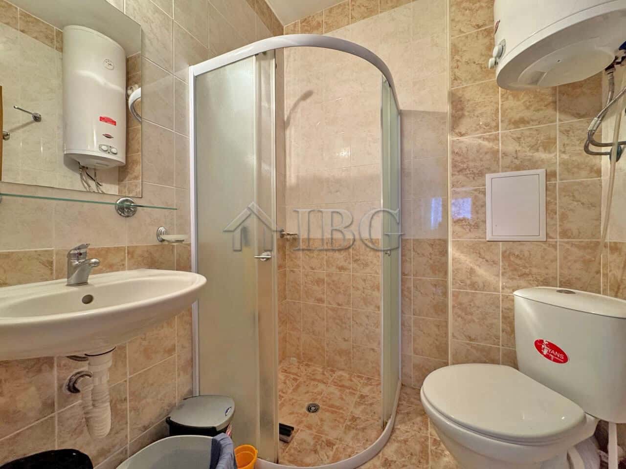 Bright bathroom with shower, toilet, and sink in a ground-floor apartment. Compact and functional de.