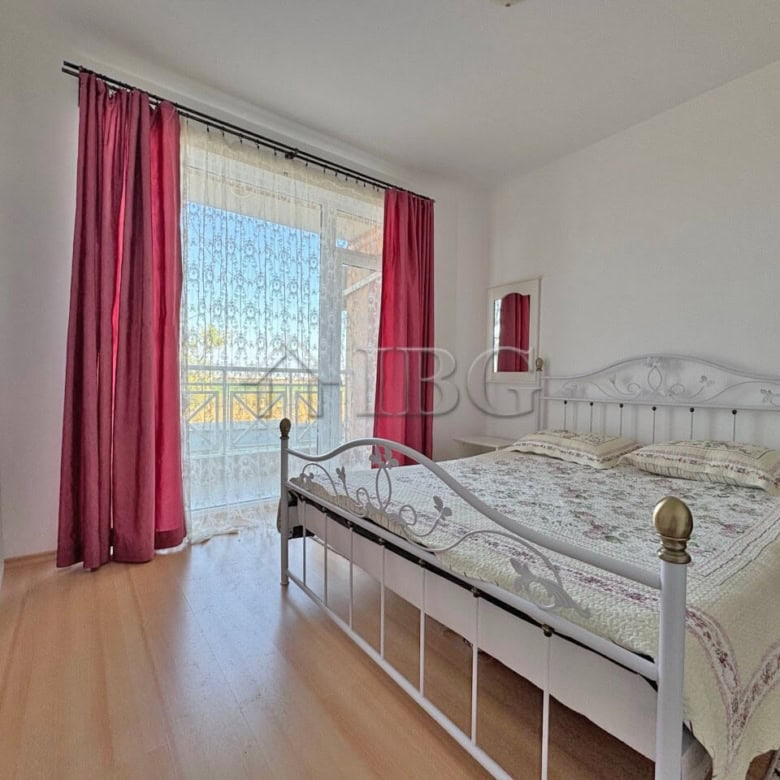 Bright bedroom with large window and balcony access, offering natural light and scenic views.