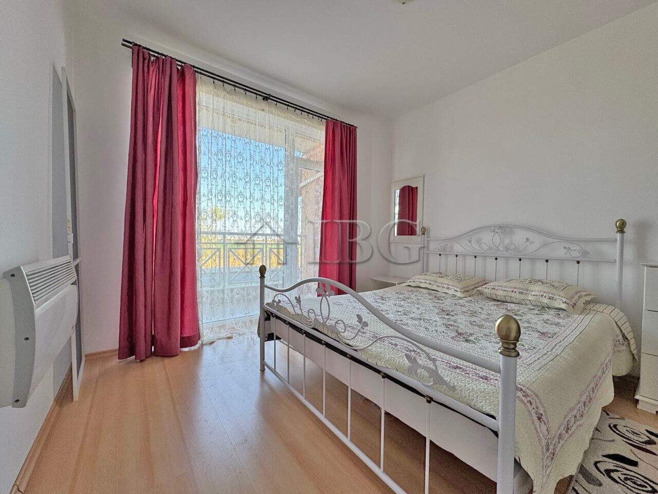 Bright bedroom with large window and balcony access, offering natural light and scenic views.