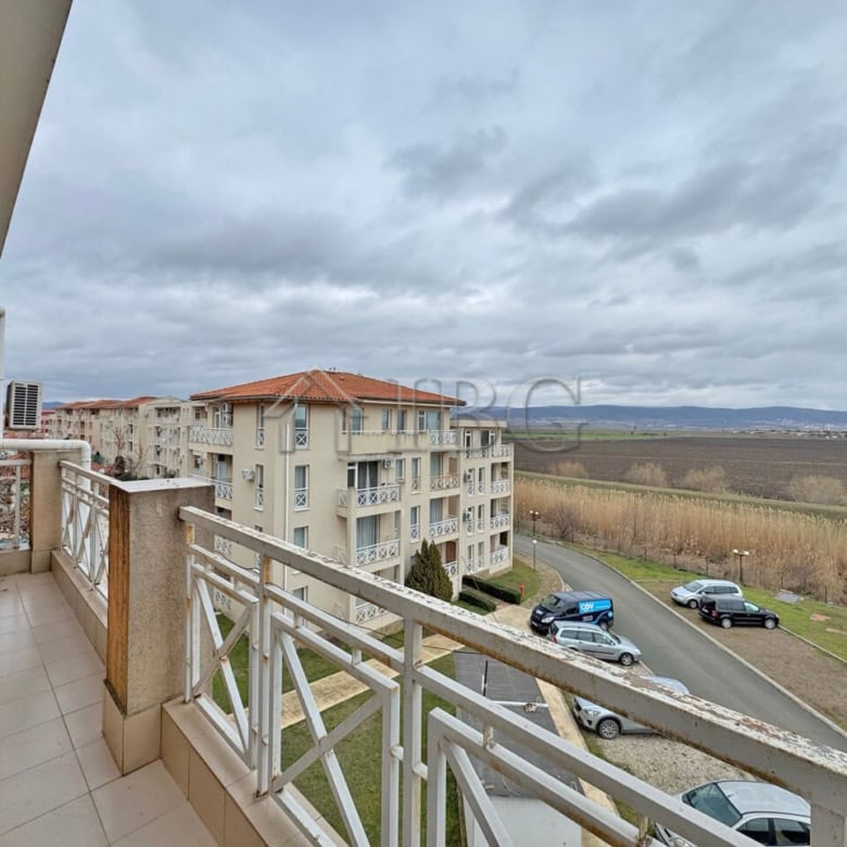Balcony view of a sunny beach and surrounding landscape from a modern 1-bedroom apartment.