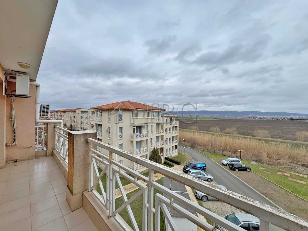 Balcony view of a sunny beach and surrounding landscape from a modern 1-bedroom apartment.
