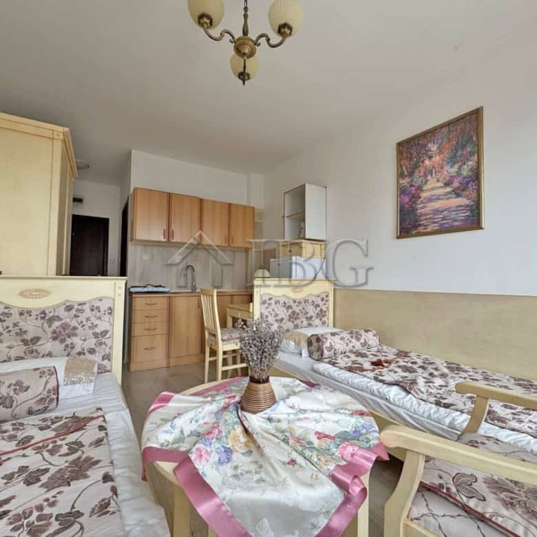 Furnished studio apartment with floral sofas, a small dining area, and a kitchenette, perfect for a.