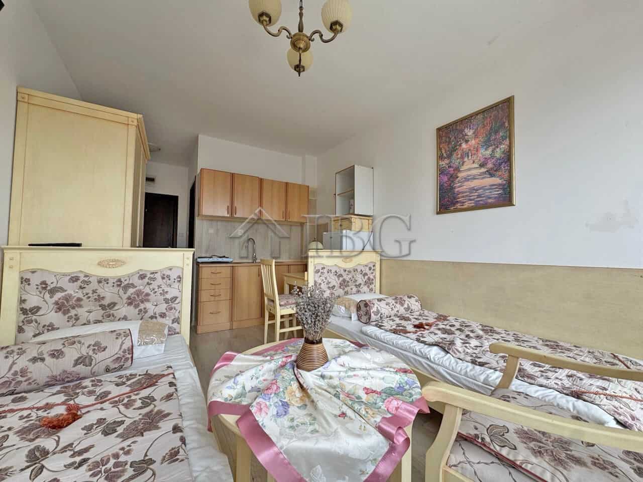 Furnished studio apartment with floral sofas, a small dining area, and a kitchenette, perfect for a.