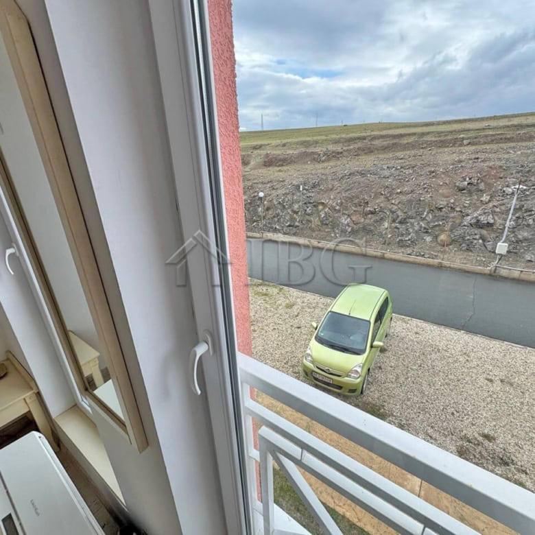 Furnished studio apartment with no balcony, overlooking sunny beach scenery on a bright day.