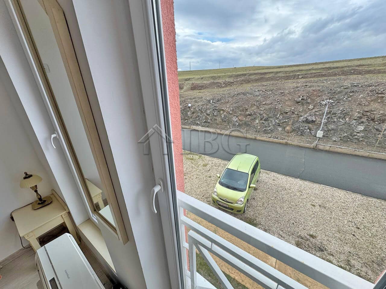 Furnished studio apartment with no balcony, overlooking sunny beach scenery on a bright day.