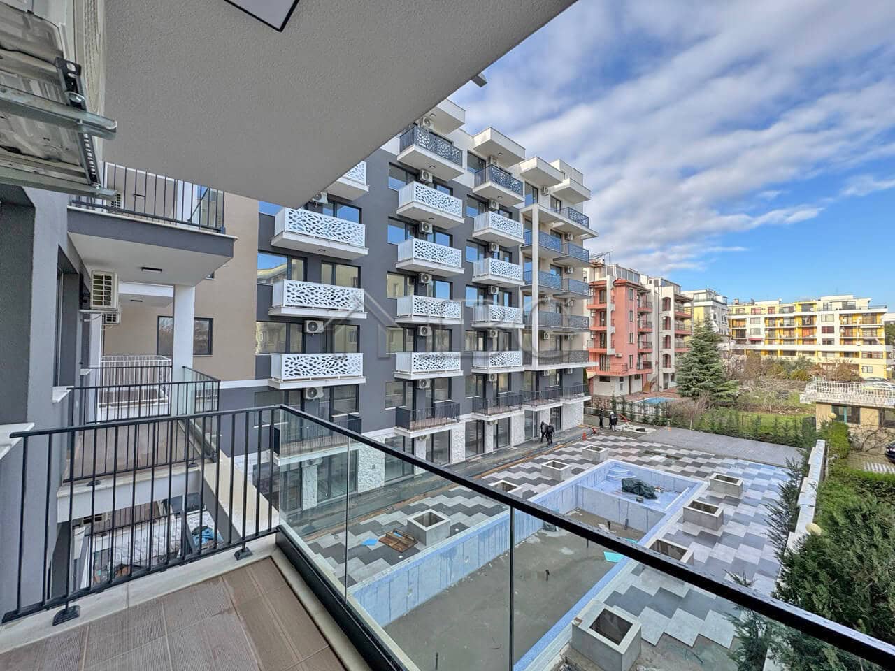 Spacious balcony overlooking pool and city views in a contemporary Sunny Beach residence.