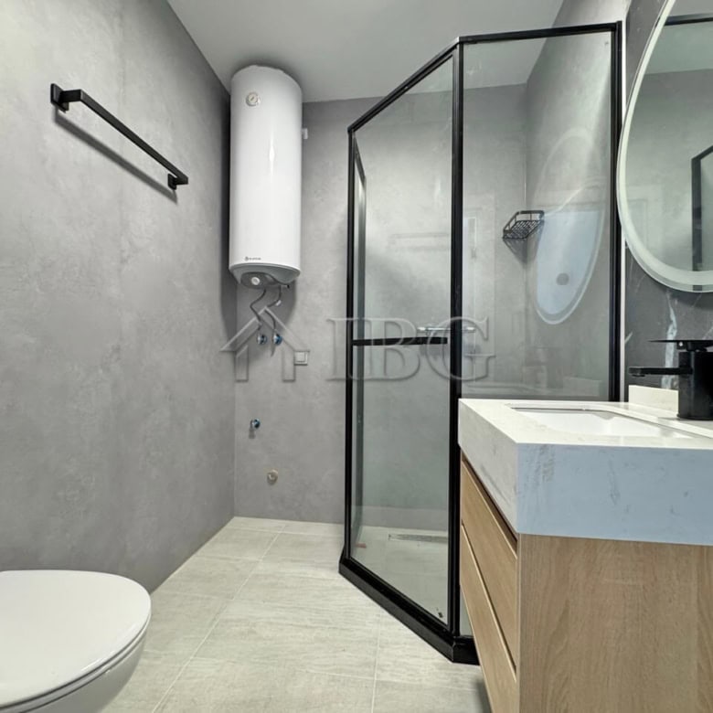 Bright bathroom featuring a glass shower enclosure, toilet, and stylish vanity with mirror.