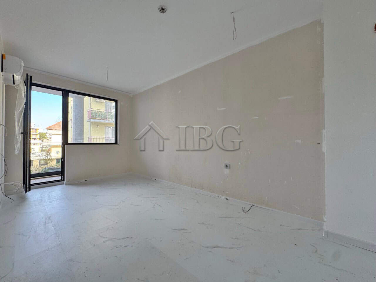 Bright empty apartment with large window and balcony access.