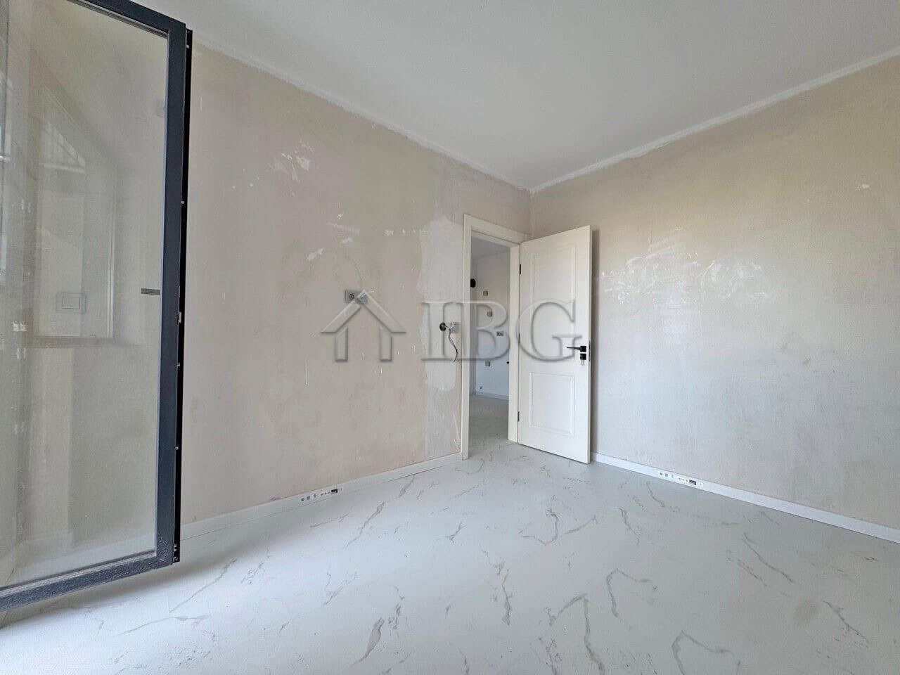 Bright empty one-bedroom apartment with large window and open door.