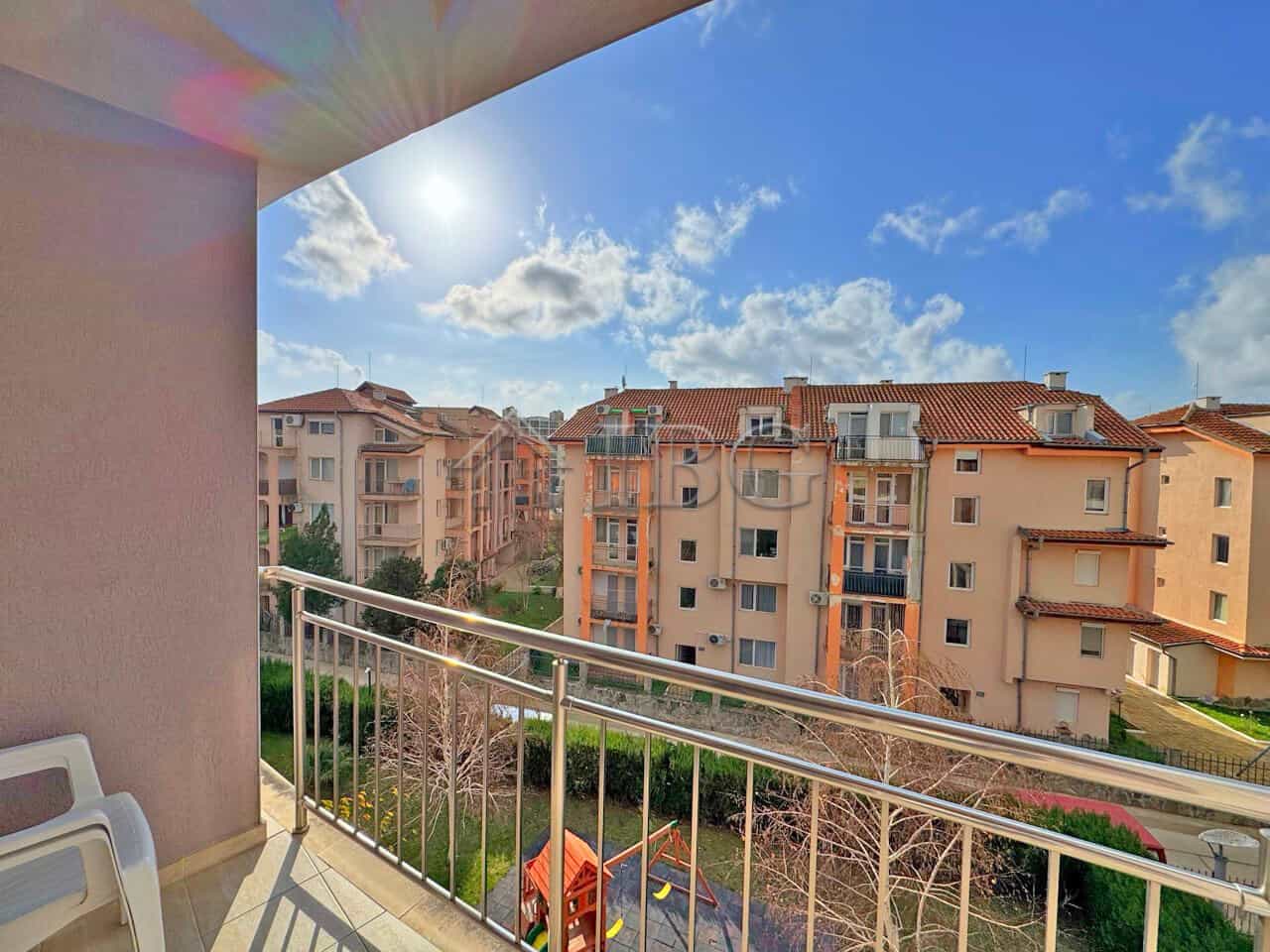 Balcony view of Sunny Beach apartments with pool and blue sky.