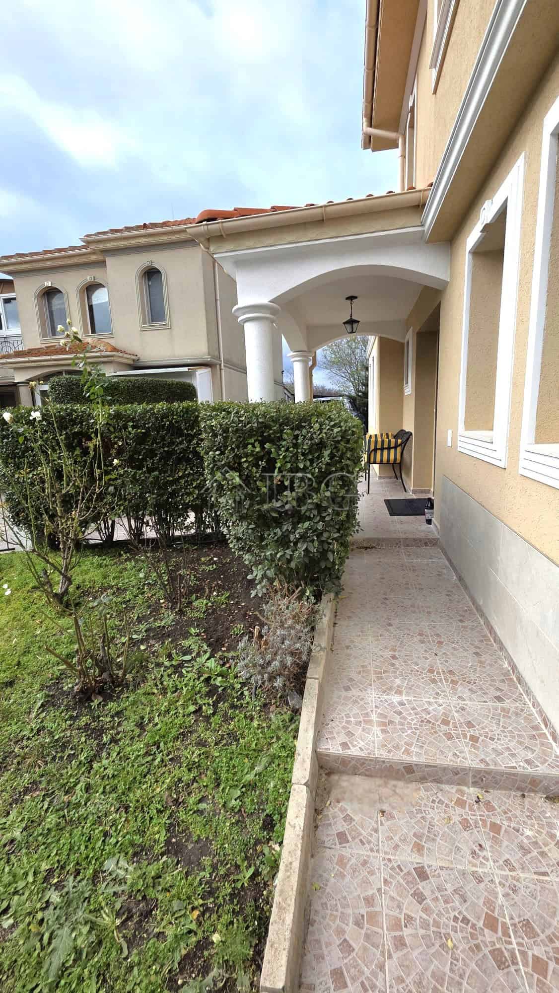 Elegant villa entrance with lush greenery and classic architecture in Pomorie.