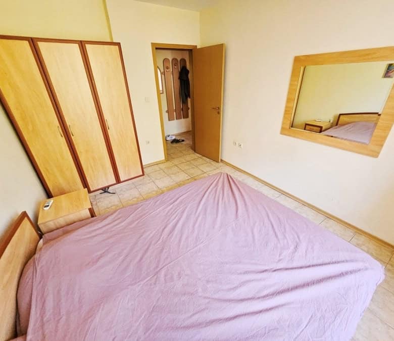 Comfortable bedroom with wardrobe and large wall mirror in a modern apartment.
