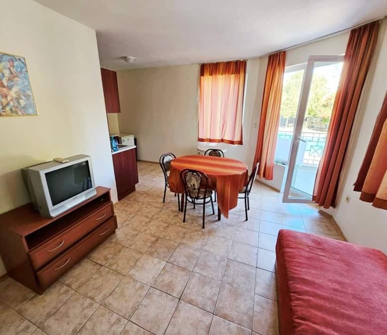 Interior of a 1-bedroom apartment with pool view, dining area, and balcony near the sea.