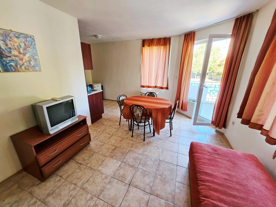 Interior of a 1-bedroom apartment with pool view, dining area, and balcony near the sea.